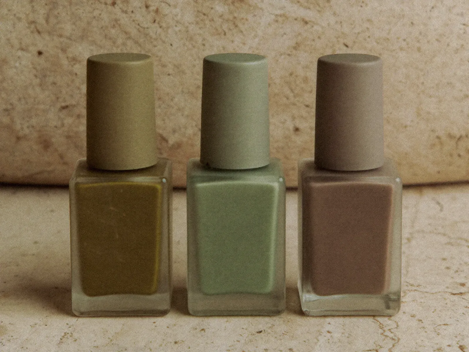 A selection of LuxeNails polishes in olive green, sage and taupe